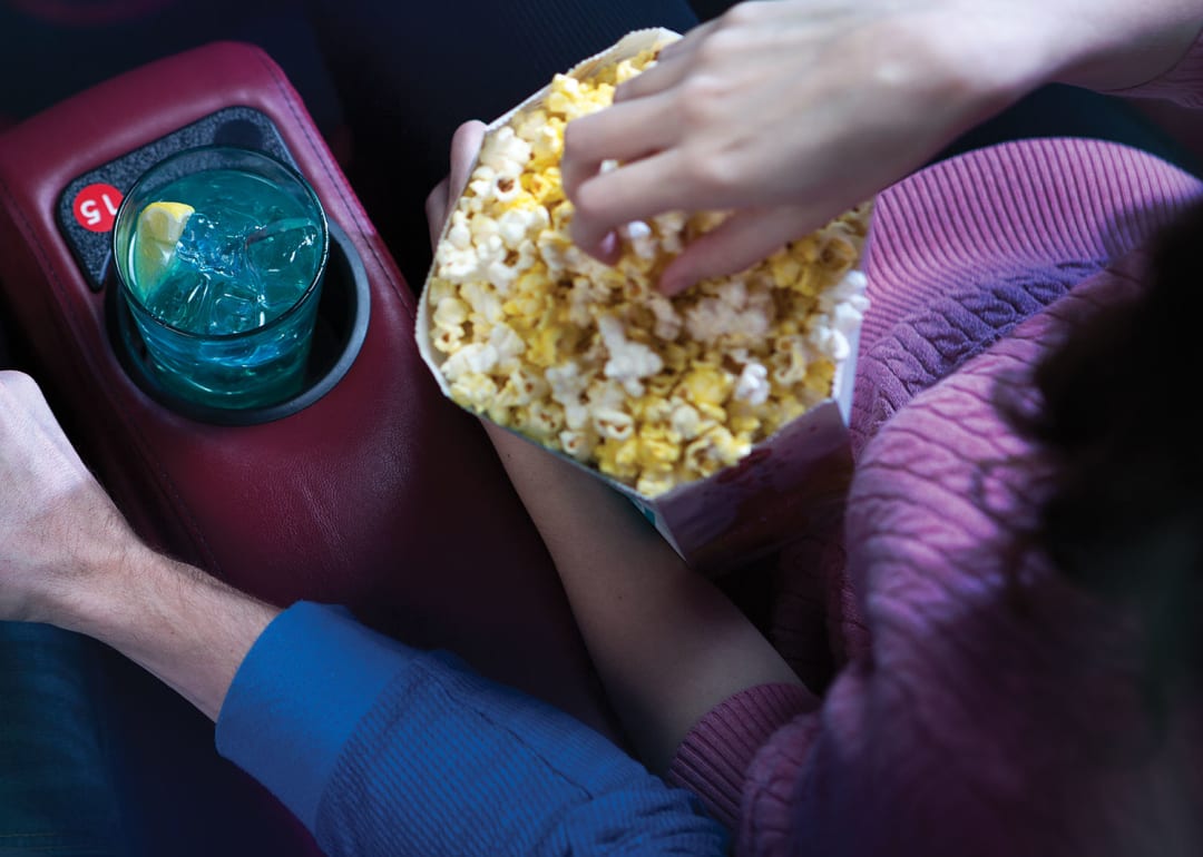 A couple in reserved seats eating popcorn.Our recliners offer a level of comfort that rivals your favorite living room chair. Available at select theatres.